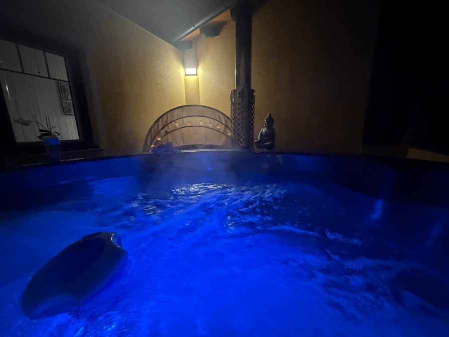 Blau beleuchtetes Wasser im Hot Tub auf einer Terrasse am Abend.