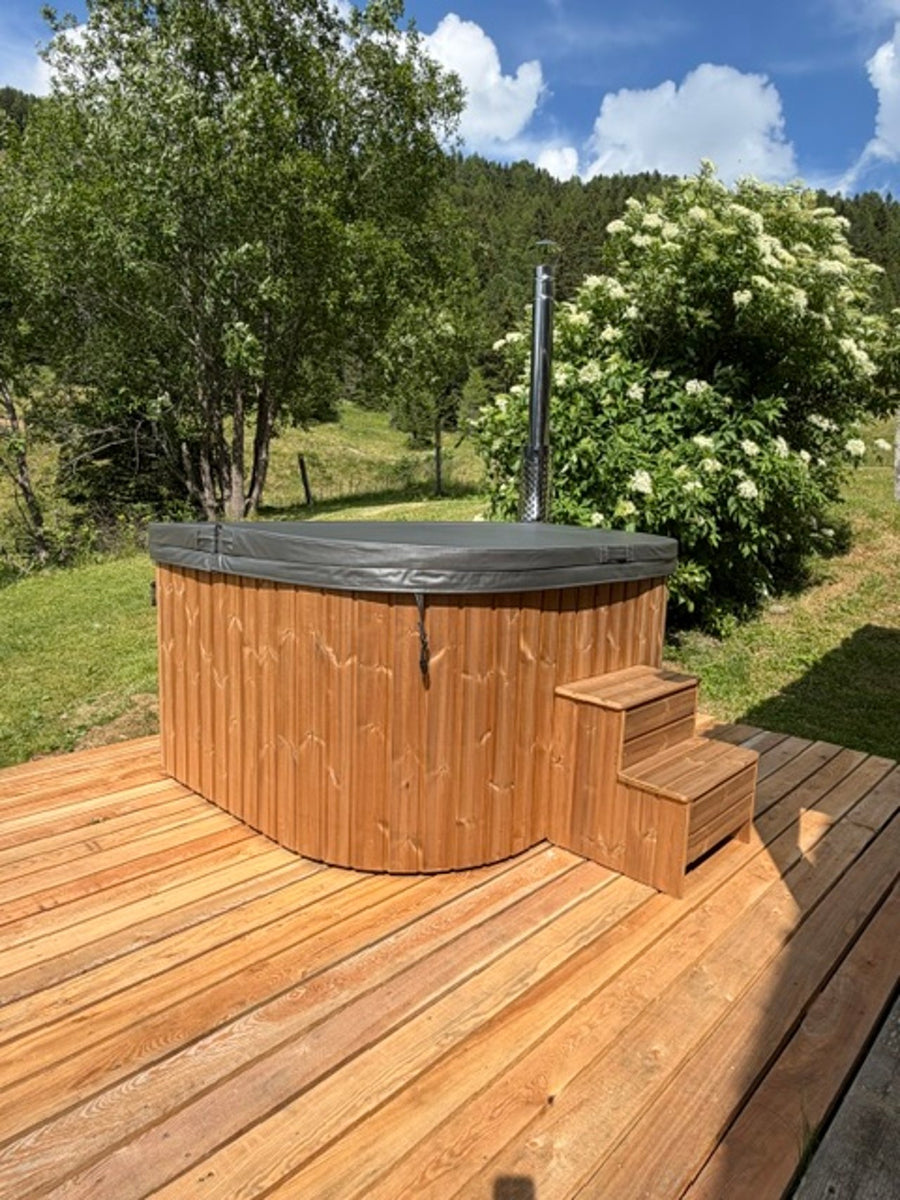Runder Hot Tub mit Holzstiege auf einem Holzdeck im grünen Garten.